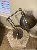 Top down view of metallic adjustable desk lamp on table showing shade and arm details.