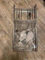 Top view of sliding metal shelf frame for trash can with mounting hardware still in plastic bags.
