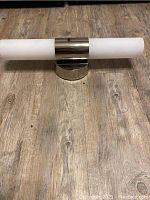 Side view of a single wall sconce showing polished metal base and white frosted glass shade horizontally mounted.