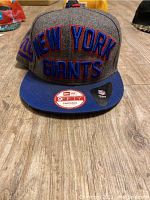 Front view of the New York Giants SnapBack hat showing blue flat brim and large 3D embroidered 'NEW YORK GIANTS' text on grey crown.
