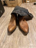 Pair of used Tony Lama cowboy boots, front view showing tan foot and pointed toe.
