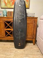 Front side view of liquid force wakeboard showing black top with design graphics