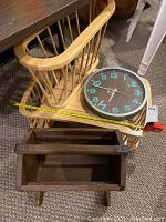 Photo showing light wood bed tray with spindle sides and the round wall clock on top, as well as the rectangular dark stained wood magazine holder.