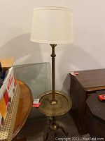 Full view of brass floor lamp with attachable tray table base and fabric lamp shade placed on top.