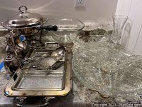 Photo of entire set showing silver plated chafing dish with lid, pitchers, glass candy dishes on pedestals, serving dish on lazy Susan with multiple glass dishes