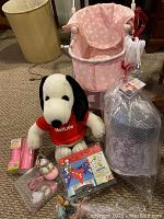 Photo showing pink polka dot PBK doll carriage, MetLife Snoopy plush toy, Vineyard Vines beach toy set box, and pink baby shoes in plastic packaging