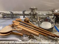 Kitchen spoons and utensils laid out on sink showing various sizes and wood wear