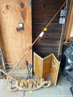 Photo showing the vintage hay rake standing upright with the fireplace tools and the Japanese screen in the background, also the wood sign on the ground