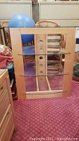 Front view of wooden frame with glass shelves and wire holes visible in back panel