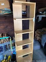 Front view of tall wooden shelf unit with five shelves, light wood color, showing scratches and signs of use.