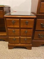 Front view of wooden side table showing three drawers with metal handles and glass top.