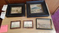Full view of all five framed wall art pieces laid out on a wooden surface for display and condition overview