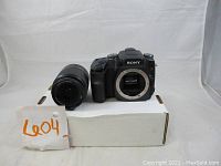 Front overview of camera body (no lens attached) and separate zoom lens on white box