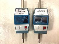 Front view of two Mitutoyo Digimatic Indicators clearly showing cracked digital screens and zero buttons.