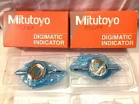Two sealed Mitutoyo Digimatic Indicators inside transparent trays with their original orange boxes labeled with model number 97215A.