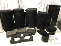 Four black Sigma EX lens carrying cases of various heights, with four foam inserts, lens hood shade, and instruction sheet arranged on table.