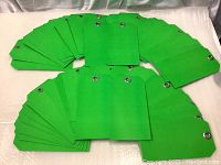 Photo showing 50 green inventory tags fanned out on a surface to display the quantity and uniformity