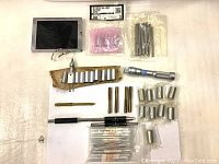 Overview of assorted Mitutoyo micrometer tool parts including sleeves, standard bars, and small precision components