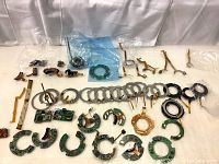 Multiple small camera lens repair parts laid out on white cloth including PCB boards, apertures, gears, and flex cables