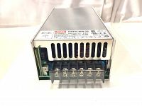 Front view of power supply showing ventilation and terminal block with labeled output connections +V and -V.