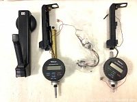 Lot showing two Mitutoyo bore gage parts with digital displays, handles, and wiring components laid out on white surface.