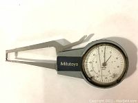 Top view of dial gauge side of the Mitutoyo dial caliper gauge showing dial face and caliper arms.