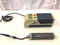 Overall view of the Mitutoyo Surftest 211 Surface Roughness Tester with connected probe lying beside it, showing body, cable, and probe details.