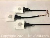 Three occupancy sensors laid horizontally displaying side profile, mounted black bracket, and exposed wiring for connection.