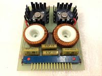 Front view of the Broncolor camera flash circuit board showing two large toroidal inductors, capacitors, heat sink mounted transistors, and a connector pin strip.