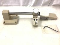 Metal components of the vertical measuring attachment with rod, dial component, and base.