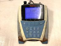 Front view of the Thermo Scientific meter showing power on with a digital screen displaying 7.09 pH and temperature of 25.0°C, metal casing rusty at the bottom sides.