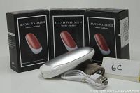 Photo showing three boxes labeled 'HAND WARMER Double sided hot' and three silver metal hand warmers along with USB charging cord and soft cases