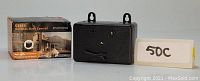 Photo of the CSB19 Outdoor Bark Control device next to its box and a label showing '50C'. Device is black rectangular with ultrasonic emitters.