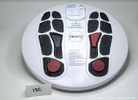 White oval plastic platform with textured black and red foot-shaped electrode pads and top-mounted control panel
