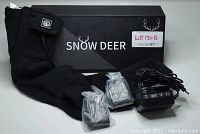 Image shows black Snow Deer heated socks with two battery chargers in plastic and one power charger with cord, set in front of the brand's box