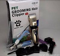 Electric pet grooming hair clipper kit with box, clipper, guide combs, nail clippers, charger, and cleaning brush.
