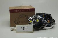 Photo showing boxed blue and orange rechargeable headlamp with three straps, six LED bulbs, and USB charging cable included.