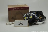 Blue and orange headlamp with five LED lights, three adjustable straps, rechargeable battery, USB charging cord, and original packaging box.