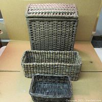 Three wicker baskets shown stacked with varying sizes and shapes, displaying the weave and colors.