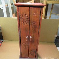 Front view of vintage wooden cabinet showing carved sun, moon, and star designs on doors.
