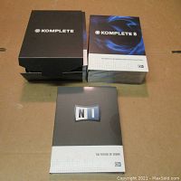 Multiple box sets of Native Instruments Komplete 8 and Komplete 10 software collections with The Future of Sound book on a cardboard surface.