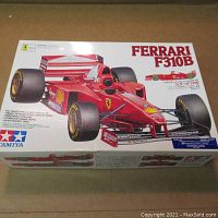 Box top of Tamiya Ferrari F310B 1/20 scale model kit showing front view of assembled car in red with sponsor decals.