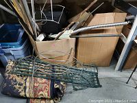 Garden trellises, rolled carpet, boxes of hardware and flexible conduit tubes on floor and shelf.