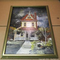 Front view of framed oil painting depicting a vintage two-story house with red roof and yellow siding against a dark sky.