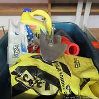 Photo showing yellow bags of safety salt with black print and yellow plastic container, along with metal scoop and other tools inside blue bin.