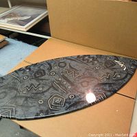 Top view of vintage skim board showing abstract black and gray design with geometric shapes.