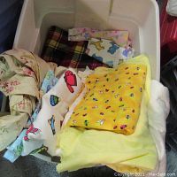 Photo of tub showing assorted fabric pieces including yellow fabric with insect prints, white with colorful dessert prints, and floral fabrics
