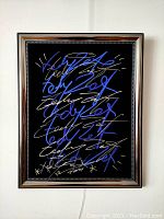 Full front image of the framed street art painting with neon layers of blue, white and gold marker over a black background.