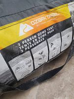 Close-up of Ozark Trail label on 3-person dome tent bag showing setup instructions.