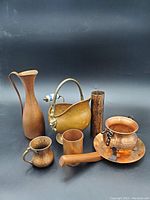 All items in the lot displayed collectively, showcasing different shapes and sizes of copper bowls, jugs, and accessories on a black background.